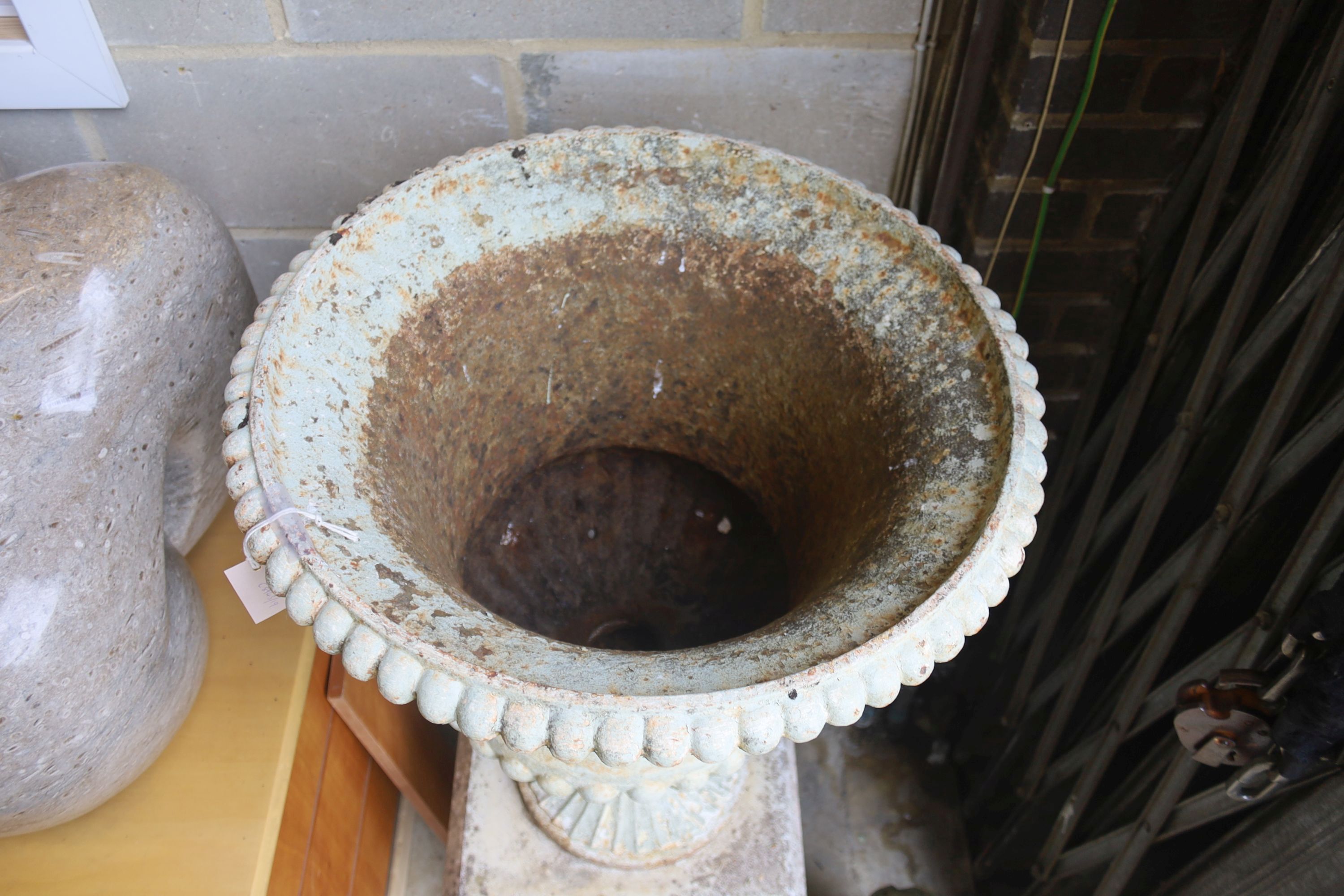 A Victorian white painted cast iron campana garden urn, diameter 56cm, height 118cm on a later reconstituted stone pedestal